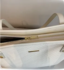 Close-up of a smooth gold zipper and woven texture on a cream-colored tote bag