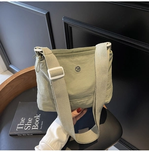 Detail of light green waterproof nylon canvas bag on a black chair with a book