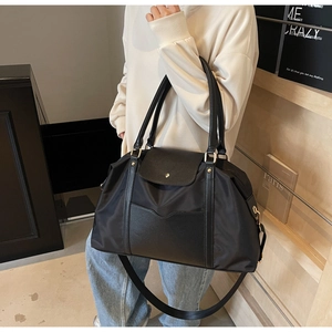 Détail d'un grand sac fourre-tout noir avec quincaillerie dorée et bandoulière réglable