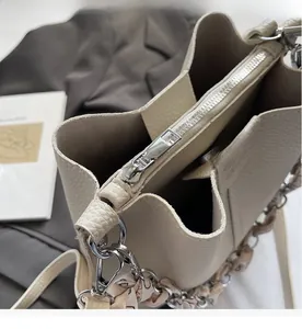 Detail of silver zipper closure and lychee texture leather on cream bucket bag