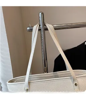 Detail of white woven tote bag featuring long handles, metallic zipper and gold rivets
