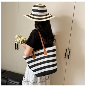Detail of a large capacity woven tote bag with black and white stripes and leather straps