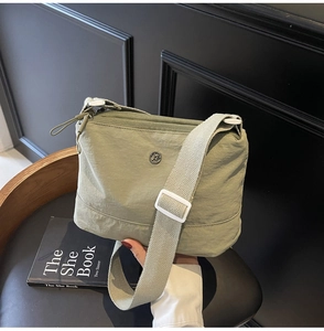 Detail of light green nylon crossbody bag showing the logo and adjustable strap