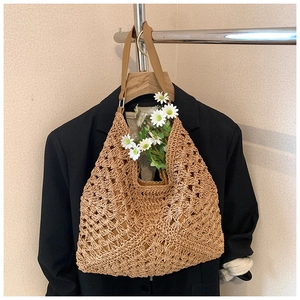 Detail of hand-woven straw tote bag with contrast crochet texture and brown leather straps