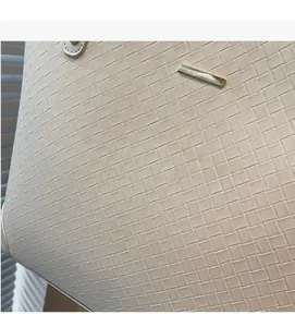 Detail of woven beige leather tote bag with elegant gold metal accent and soft texture
