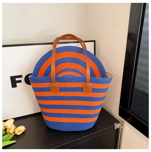 Detail of blue and orange striped straw tote bag with brown leather handles and matching hat