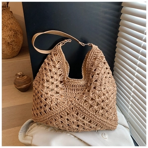 Detail of the hollow-out crochet texture on a khaki woven summer straw shoulder bag