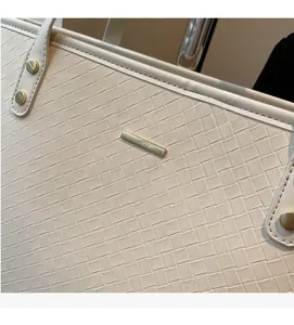 Detail of cream woven leather tote bag featuring gold hardware and Intrecciato pattern