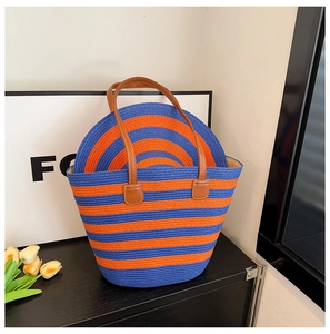 Detail of blue and orange striped straw woven tote bag with brown leather handles