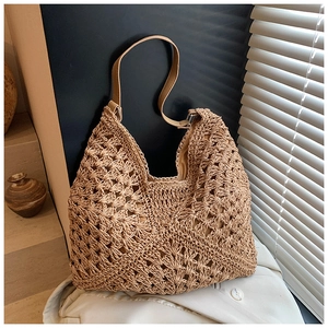 Detail of hollow woven straw beach bag with brown leather shoulder strap and fabric lining