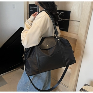 Détail d'un grand cabas en nylon noir avec rabat en cuir porté par un mannequin femme