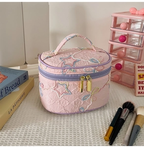 Detail der Stickerei auf einer gesteppten rosa Kosmetiktasche mit Sternen und Schmetterlingen