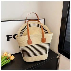 Detail of woven straw tote bag with matching striped sun hat and brown leather handles