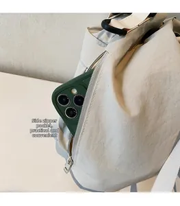 Detailweergave van het ritsvak aan de zijkant van een beige canvas rugzak voor een telefoon