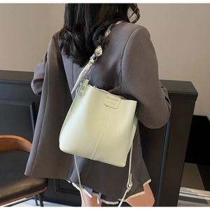 Detail of light green litchi texture bucket bag with silk scarf on shoulder strap