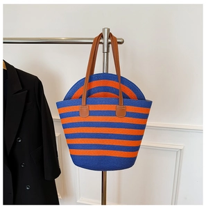 Detail of blue and orange striped straw tote bag and matching sun hat on a rack