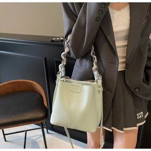 Detail of light green bucket bag with lychee texture and silk scarf wrapped chain handle