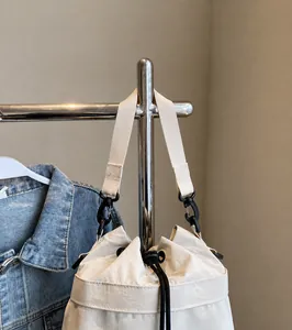 Detail van gebroken witte canvas emmer tas met geweven riem en zwart trekkoord