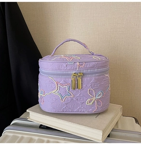Detail der lila Kosmetiktasche mit Stickerei, Sternmuster und goldenem Reißverschluss