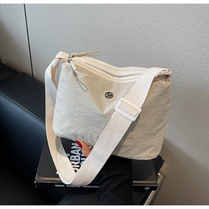 Close-up of beige canvas crossbody bag with wrinkled texture and wide woven strap