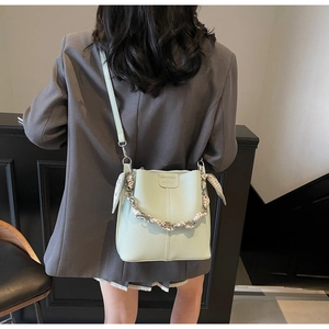 Close-up of mint green litchi grain leather bucket bag with silk scarf handle detail