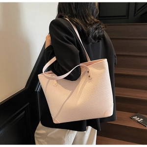 Close-up of a light pink tote bag featuring a cross-woven texture and long shoulder straps