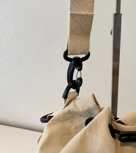 Detailopname van de duurzame zwarte draaihaak en de versterkte canvas schouderriem van de tas