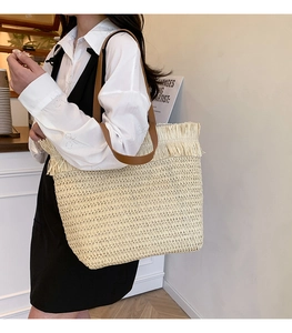 Detail of hand-woven straw tote with leather straps and fringe trim for summer