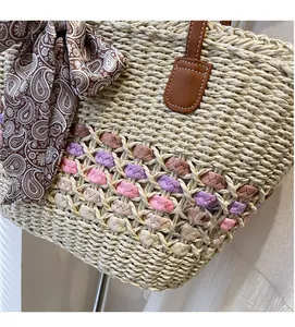 Detail of hand-woven straw bag featuring colored bands and a brown scarf-wrapped handle