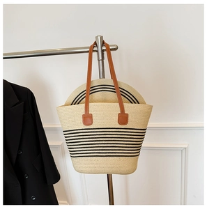 Detail of straw tote bag and hat set with black stripes and brown leather handles