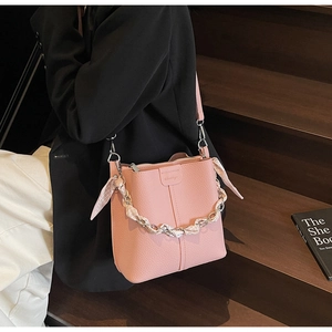 Pink lychee grain leather bucket bag with metal chain handle and polka dot silk scarf detail