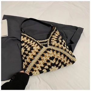 Detail of bohemian geometric woven hobo bag with black leather strap on a grey suit