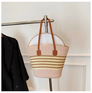 Detail of hand-woven straw tote with brown stripes and matching summer hat