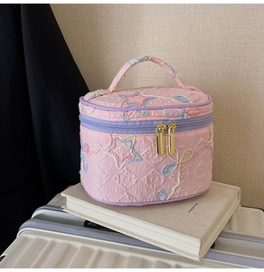 Detail der rosa gesteppten Kosmetiktasche mit Sternstickerei und goldenem Reißverschluss