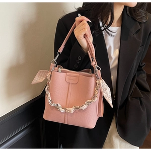 Pink lychee grain bucket bag with heart scarf-wrapped chain and brand logo detail