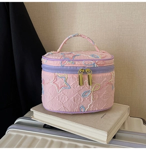 Rosa gesteppte Kosmetiktasche mit Sternstickerei und lila Reißverschluss auf Reisen
