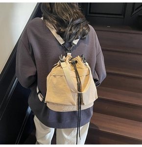 Detail van beige nylon bucket rugzak met trekkoord, zijzakken en stoffen banden