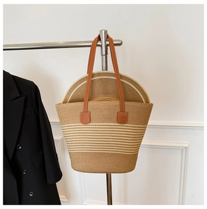 Detail of straw tote bag with brown leather handles and matching woven sun hat set