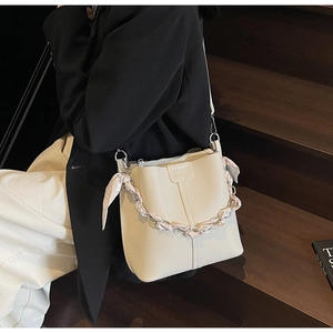 Detail of cream bucket bag with lychee pattern leather and silk scarf chain handle