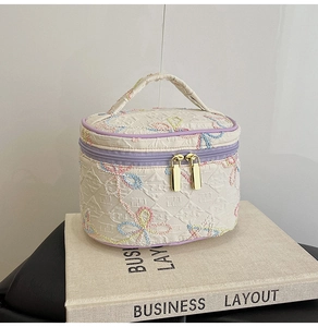 Detail der gesteppten Kosmetiktasche mit bunter Schleifenstickerei und Doppelreißverschluss