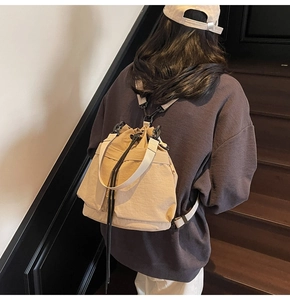 Model met een kaki canvas bucket rugzak met trekkoord en crèmekleurige schouderbanden