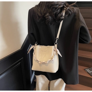 Close-up of cream bucket bag featuring lychee texture and silk scarf wrapped chain handle