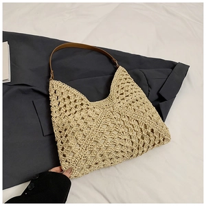 Close-up of the hollow woven texture and brown leather strap on the summer straw bag