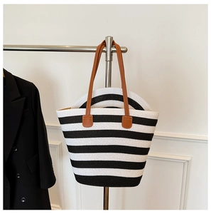 Detail of striped straw tote bag and matching hat set with brown faux leather handles