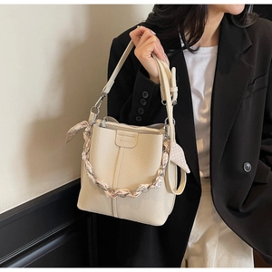 Detail of cream bucket bag with lychee texture and silk scarf wrapped chain handle