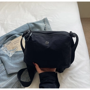 Detail view of black multi-layer nylon crossbody bag with three zipper pockets and wide strap