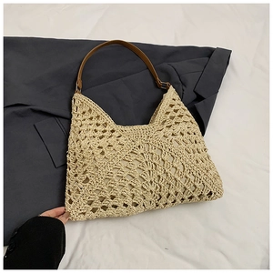 Detail of hollow woven beige straw beach tote with premium brown leather shoulder strap