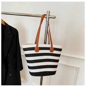 Detail of black and white striped straw tote bag with brown faux leather straps