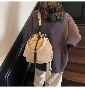 Achteraanzicht van beige nylon bucket rugzak gedragen op een houten trap