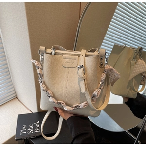 Detail of cream bucket bag showing lychee texture and silk scarf metal chain strap